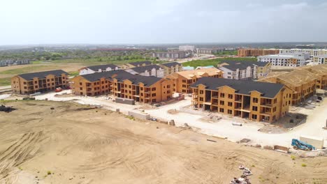 Aerial-Drone-View-of-Apartment-Homes,-Roofs,-Trusses,-Cranes,-Boom-Lifts,-Tractors,-Roads,-Cars,-Traffic---Residential-Building-Construction-Site-In-Austin,-Texas,-USA