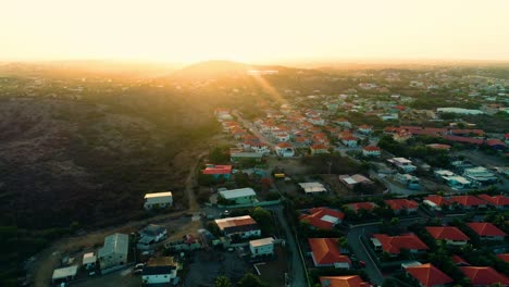 4k-cinematic-drone-video-of-houses-and-neighborhoods-on-the-Caribbean-island-of-Curacao,-during-golden-hour-sunset-with-flare