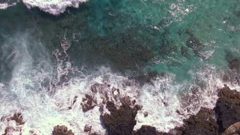 Aerial-view-of-rocky-Hawaiian-coastline-in-Pacific-Ocean-top-down