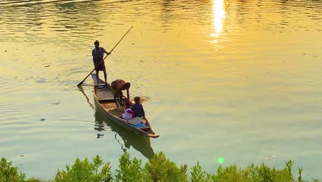 Fisherman-dropping-fishing-net-in-river-by-boat-at-morning-sunlight-at-Surma-river-in-Sylhet,-Bangladesh