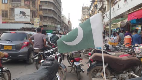 Pakistanische-Flagge-Weht-Mit-Blick-Auf-Die-Belebte-Saddar-Marktstraße-Im-Hintergrund