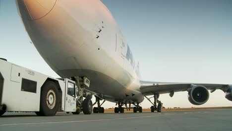 Airport-worker-pushback-big-white-cargo-airplane-to-runway-with-aircraft-puller