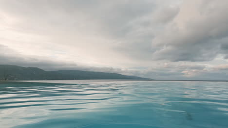 Serene-ripples-across-gorgeous-infinity-pool,-under-dramatic-sky