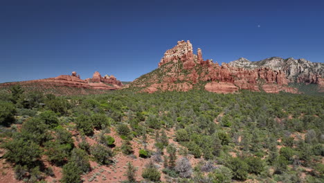 Aerial-over-landscape-with-trees-toward-striking-red-rock-formations-of-Sedona
