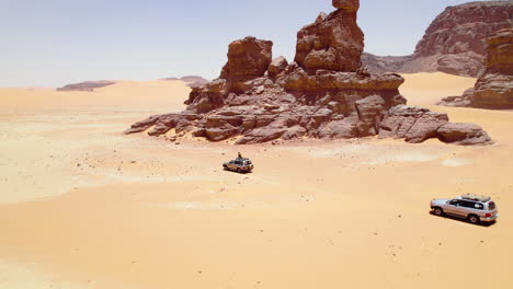 Vehicles-Driving-Around-The-Sand-Dunes-Of-The-Sahara-Desert-In-Algeria---aerial-drone-shot
