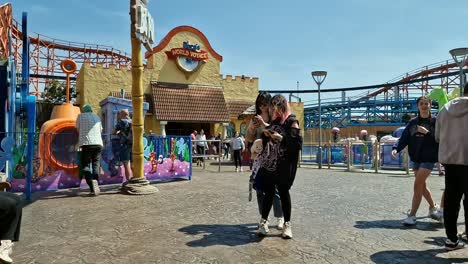 Walking-through-Blackpool-pleasure-beach-amusement-park-with-tourists-visiting-attractions