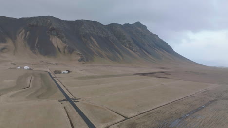 Toma-De-Drones-De-Caminos-Rurales-Y-Casas-En-El-Desierto-De-Islandia,-Paisajes,-Casas-Y-Colinas-Volcánicas