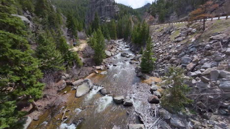 FPV-drone-flight-in-Colorado-mountains-over-river-through-trees-next-to-road