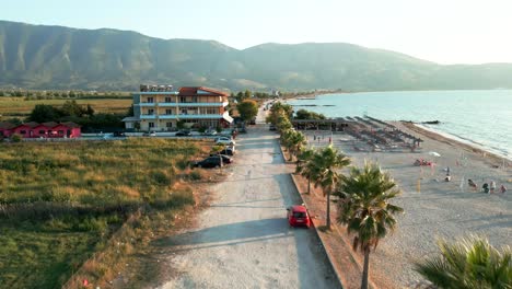 Albania,-road-along-the-beach,-palm-trees,-sea,-and-mountains-in-the-background