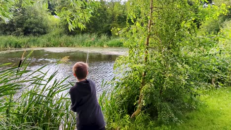 4K-60FPS-Boy-Casting-His-Fishing-Tackle-Into-Tree-While-Fishing-in-Pond-in-Denmark,-Scandinavia