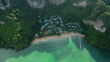 Small-Thailand-village-on-sandy-coast-surrounded-by-mountains,-aerial-view