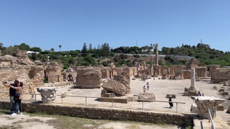 Tourists-take-photos-and-visit-the-Baths-of-Antoninus-or-Baths-of-Carthage,-located-in-Carthage,-Tunisia,-which-are-the-largest-sets-of-Roman-thermae-built-on-the-African-continent