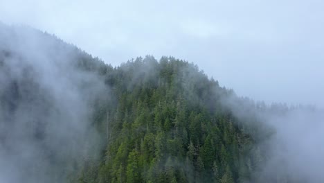 Dramatic-Aerial-Through-Clouds-Revealing-Rugged-Forest-Shrouded-in-Fog