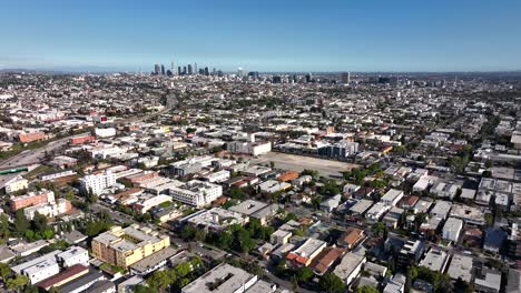 Hollywood-neighborhood-of-apartments-and-businesses-on-a-hot-clear-blue-sky-afternoon,-aerial-forward-view-in-city-of-Los-Angeles