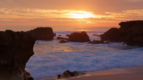 Wellen-Schlagen-Bei-Sonnenuntergang-An-Der-Algarve,-Portugal,-Auf-Die-Felsformationen-Am-Strand