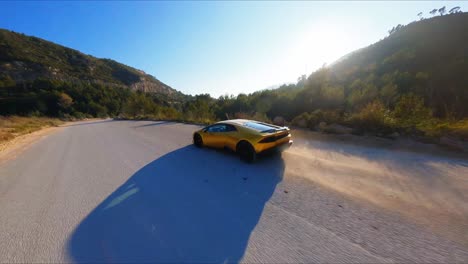 FPV-Luftaufnahme-Eines-Wunderschönen-Gelben-Lamborghini-Entlang-Einer-Malerischen-Landstraße