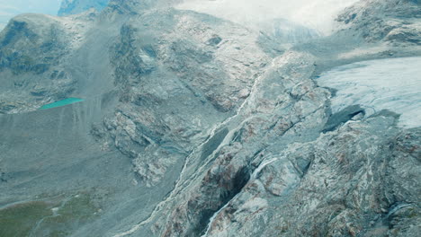 Riesiger-Wasserfall,-Der-Von-Einem-Gletscher-Kommt,-Der-Aufgrund-Des-Klimawandels-In-Den-Alpen-In-Einem-See-Schmilzt,-Große-Fellaria-Wasserfälle-Stürzen-Vom-Rand-Des-Gletschers-Herab,-Blick-Von-Oben-Auf-Die-Berge-Und-Den-See-Darunter