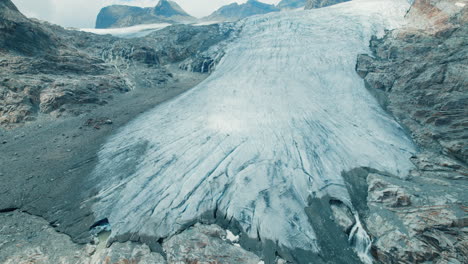 Riesiger-Wasserfall,-Der-Von-Einem-Gletscher-Kommt,-Der-Aufgrund-Des-Klimawandels-In-Den-Alpen-In-Einem-See-Schmilzt,-Große-Fellaria-Wasserfälle-Stürzen-Vom-Rand-Des-Gletschers-Herab,-Blick-Von-Oben-Auf-Die-Berge-Und-Den-See-Darunter