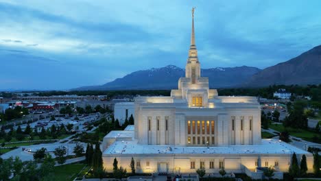 LDS-Mormon-Temple-in-Ogden-Utah-drone-flight-flying-at-dusk-on-beautiful-summer-night-as-camera-slowly-pans-around-the-south-side-of-golden-religious-building-at-night