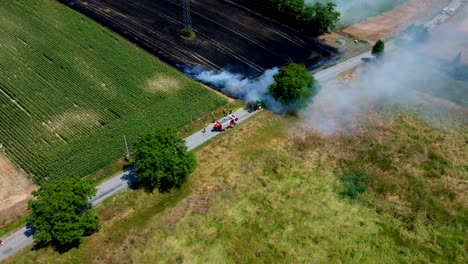 Firemen-Attending-Fire-In-Agricultural-Field---aerial-drone-shot