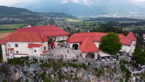 Turista-Visitando-El-Castillo-En-La-Cima-De-La-Colina-Im-Bled-Con-Paisaje-Escénico-En-El-Fondo,-Eslovenia