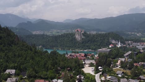 Aufsteigende-Drohnenaufnahme,-Die-Die-Stadt-Bled-Mit-Dem-Berühmten-See-Und-Der-Burg-Auf-Dem-Hügel-Im-Hintergrund-Zeigt