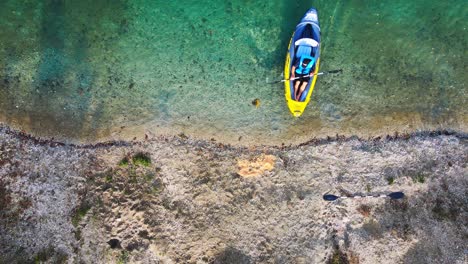 Stunning-aerial-4K-drone-footage-of-a-kayaker-approaching-the-lake's-banks-and-disembarking