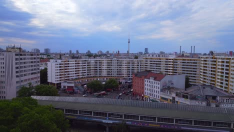 Dramatic-aerial-top-view-flight-City-Berlin-suburban-railroad-station-Kottbussertor-prefabricated-building-skyscrapers-district-Neukoeln,-Germany-Summer-day-2023-overflight-flyover-drone-4K-Cinematic