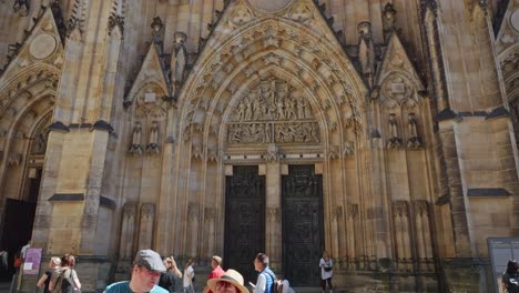 Turists-under-the-majestic-front-wall-of-Metropolitan-Cathedral-of-Saints-Vitus,-Wenceslaus-and-Adalbert,-a-Roman-Catholic-metropolitan-cathedral-in-Prague,-Czech-Republic