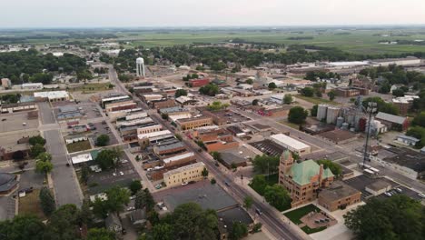 Aerial-view-of-rural-small-town-with-small-business-and-houses-in-the-late-evening,-cornfields-in-background