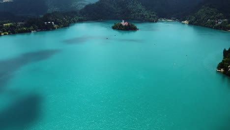 Aerial-tilt-up-shot-of-blue-colored-Bled-Lake-with-famous-island-and-Mother-of-God-Church,-Slovenia