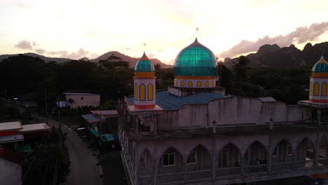 Aerial-orbiting-shot-of-asian-mosque-in-Thailand-,-Ao-Nang-during-sunset-time-and-sunlight-shining-through-glasses-of-blue-cupola