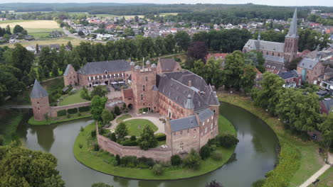 kasteel-huis-bergh,-the-netherlands:-aerial-view-in-orbit-of-the-beautiful-castle-and-appreciating-the-moat,-the-towers-and-the-nearby-church