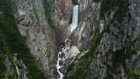 Aerial-top-down-shot-of-Boka-Waterfall-crashing-down-in-mountain-ravine-during-sunny-day,-Posocje,-Slovenia