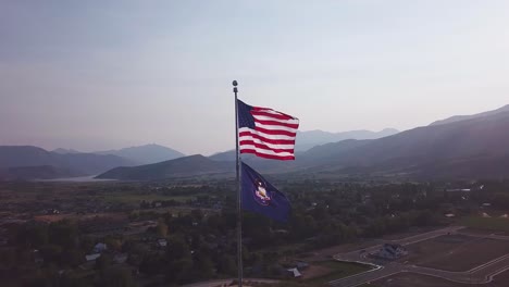 Bandera-Estadounidense-Y-Bandera-Del-Estado-De-Utah-Ondeando-En-El-Viento-En-Memorial-Hill,-Midway-Utah