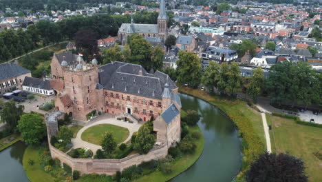 kasteel-huis-bergh,-netherlands:-close-up-aerial-view-traveling-in-to-the-beautiful-castle-and-appreciating-the-moat-and-the-nearby-church