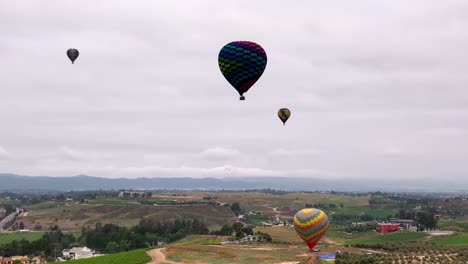 Aerial-view-of-Hot-air-balloons-rising,-cloudy-day-in-Temecula,-California,-USA