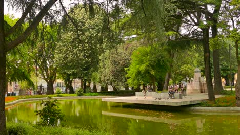 Menschen-Entspannen-Sich-In-Der-Nähe-Des-Teiches-Im-Jardim-Da-Cordoaria,-Porto,-Portugal-–-Schwenken