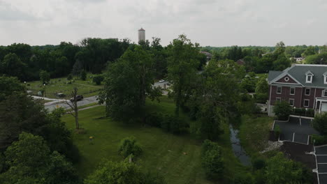 Aerial-rising-in-Indiana-state-park-in-Lawrence,-water-tower-on-distance