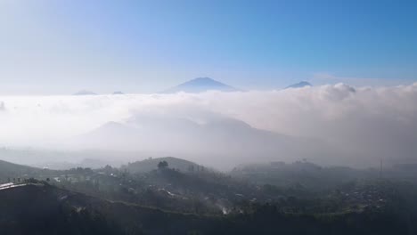 Aerial-view-of-countryside-on-the-mountain-slope-with-view-sea-of-clouds-and-mountain-range---Rural-landscape-of-Indonesia