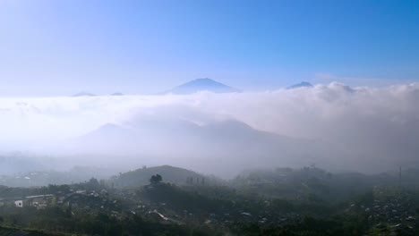 Aerial-view-of-countryside-placed-on-the-hills-with-view-of-sea-of-clouds-and-mountain-range---Rural-landscape-of-Indonesia