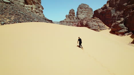 Man-Walking-In-Sand-Dunes-In-Sahara-Desert,-Algeria---aerial-drone-shot