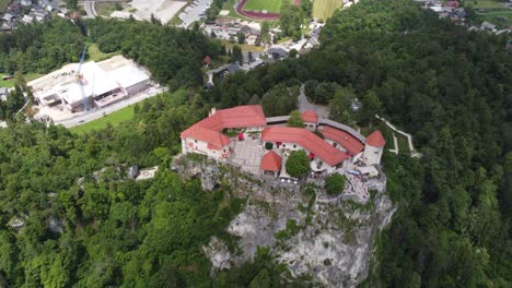 Aerial-top-down-shot-of-famous-Slovenian-castle-on-top-of-green-hill-in-Bled-during-summer-day