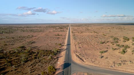 Aerial-view-above-90-miles-straight-road,-australia-on-a-sunny,-desert-outback,-tilt-,-drone-shot