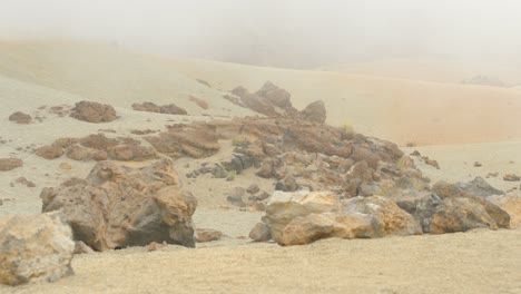 View-at-massive-pumice-stones-on-yellowish-sand-in-foggy-national-park-Teide