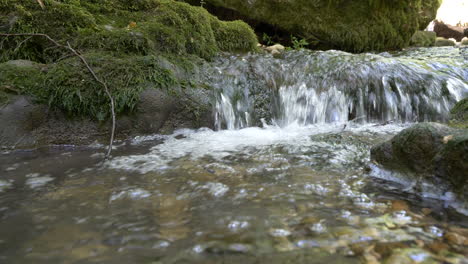 Clear-water-of-Stream-floating-down-the-mossy-hill-during-sunny-day,low-angle-shot