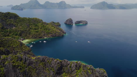 Cinematic-aerial-footage-tilt-up-of-the-cliffs-and-bays-of-palawan-with-the-ocean-in-bright-blue-at-daylight,-Palawan,-Philippines,-Asia,-Drone