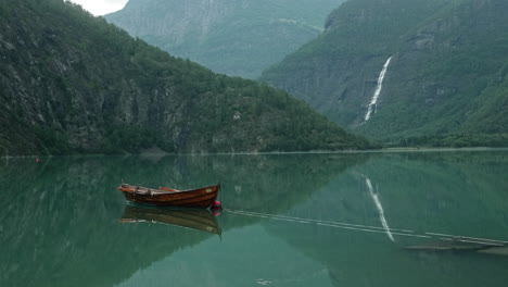 Stunning-View-of-a-Wooden-Rowing-Boat-attached-on-a-Buoy-on-a-Beautiful-Calm-Lake-in-a-Norwegian-Fjord-with-Intense-Water-Reflections,-Norway,-Mountains