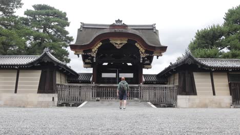 Tourist-walking-towards-the-massive-wooden-gate-at-Kyoto-imperial-palace
