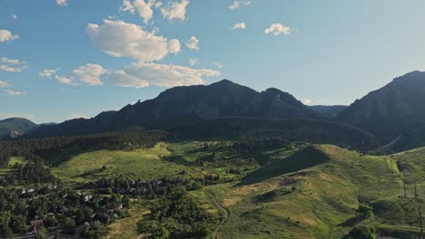 Aerial-over-the-forested-hills-of-Boulder-with-the-Flatirons-mountain-peaks-in-the-background,-Colorado,-USA